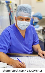 Male Anesthesiologist In Uniform Writing A Medical Chart For Documentation