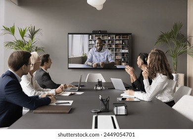 Male applicant pass job interview remotely using video call. Group of HR managers interviewing African candidate through videoconference. Communication using videocall app, virtual business meeting - Powered by Shutterstock