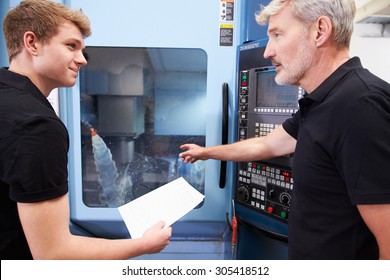 Male Apprentice Working With Engineer On CNC Machinery