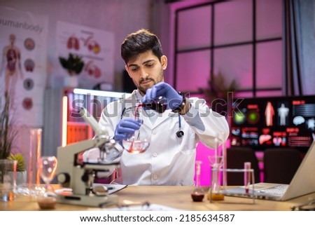 Male arab scientist working in modern lab. Doctor making microbiology research. Laboratory tools: microscope, test tubes, equipment. Coronavirus covid-19, bacteriology, virology, dna and health care.