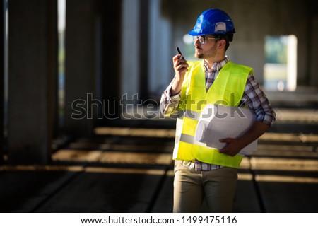 Male architect communicating on walkie-talkie at site