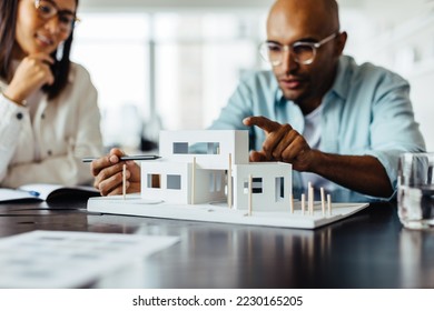 Male architect discussing a 3D house model with his colleague in an office. Creative business people working on a new building design project. - Powered by Shutterstock