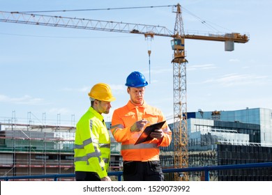 Male Architect Giving Instructions To His Foreman On Clipboard Working At Construction Site
