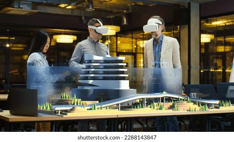 Male architect uses VR headset and wireless controllers, presents modern hi-tech building and park architectural project in virtual reality to colleagues. 3D hologram. Future digital AI technologies. - Powered by Shutterstock