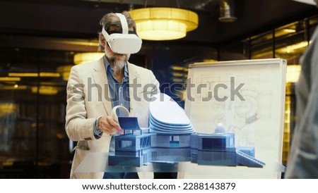 Male architect uses VR headset and wireless controllers, presents modern futuristic building project in virtual reality cyberspace to coworkers. 3D hologram. Future innovative digital AI technologies.