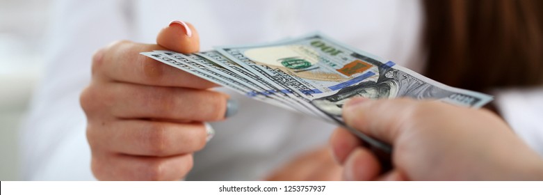 Male arm pay bunch of hundred dollars bills to office clerk closeup. Bribery accept backhander banknote venality laundering back scheme offshore company irs kickback collusion lobby gift compensation