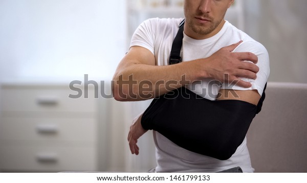 Male in arm sling suffering pain in shoulder,\
result of work trauma,\
orthopedics