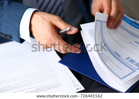 Male arm in suit offer insurance form clipped to pad and silver pen to sign closeup. Strike a bargain, driver money loss prevention, secure road trip, harmless drive idea, owner protective concept