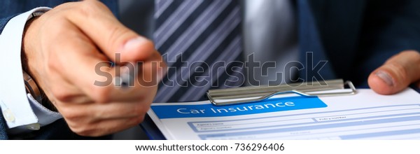 Male arm in suit offer insurance form clipped to\
pad and silver pen to sign closeup. Strike a bargain, driver money\
loss prevention, secure road trip, harmless drive idea, owner\
protective offer