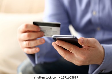 Male Arms In Suit Hold Credit Card And Phone Make Transfer Closeup. Anti-fraud Financial Security When Entering Client Discount Program Number Or Filling Personal Credential Password Login To Account