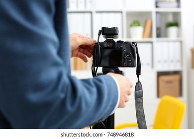 Male arms in suit mount camcorder to tripod making promo videoblog or photo session in office closeup. Vlogger adjust set up and check image quality to show job offer promotion selfie information - Shutterstock ID 748946818