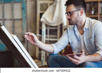 Male art school artist painting with oil on canvas