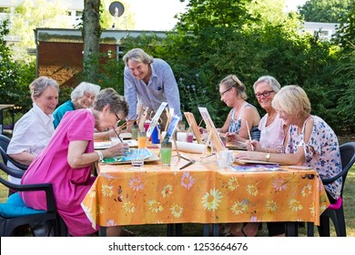 Male artist giving art lessons to the group of senior women, practicing in painting pictures sitting at one table outdoors in backyard. - Powered by Shutterstock