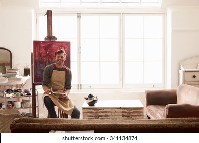 Male Artist Working On Painting In Bright Daylight Studio