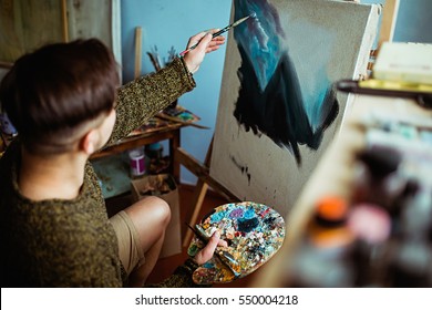 Male Artist Working On Painting In Bright Daylight Studio