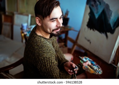 Male Artist Working On Painting In Bright Daylight Studio