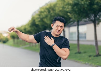 Male Asian Athlete, Kneading Shoulder Pain, Sore Arm Muscles In The Park