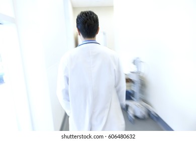 Male Asian Chinese Hospital Physician In White Coat In Corridor Of Modern Medical Centre Motion Blur