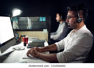 Male Asian Customer Service Telemarketing Agent Working Night Shift In Call Center Office