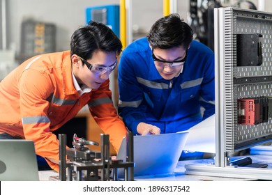 Male Asian Engineer Professional  Having A Discussion Standing By The Machine In The Factory ,two Asian Coworker Brainstorm  Explaining And Solves The Process Of The Machine.