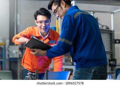 Male Asian Engineer Professional  Having A Discussion Standing By The Machine In The Factory ,two Asian Coworker Brainstorm  Explaining And Solves The Process Of The Machine.