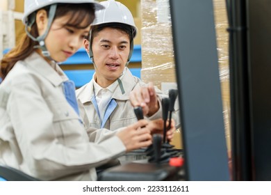 male asian engineer teaching to female driver how to operate a forklift - Powered by Shutterstock