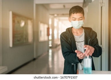 A Male Asian High School Student Is Wearing The Mask And Cleaning His Hands With Alcohol Gel Before Come In The Classroom In The Midst Of Coronavirus Disease 2019 (COVID-19) Epidemic.