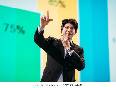 Male Asian Speaker Stands On Stage For Business Presentation 