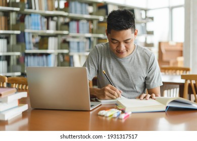 Male Asian Student Studying And Reading Book In Library