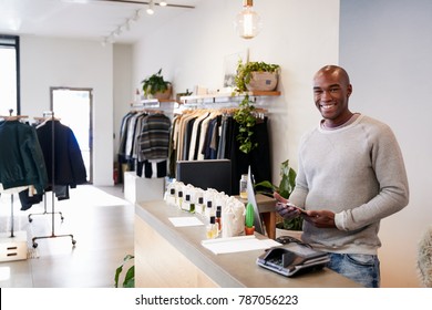 Male Assistant Smiling Behind The Counter In Clothing Store