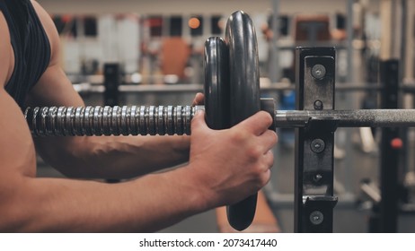 The male athlete changes the weight on the barbell. - Shutterstock ID 2073417440