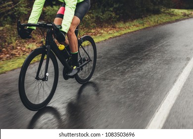 Male athlete in cycling gear riding bike on wet road. Low section shot of cyclist training outdoors on a rainy day. - Powered by Shutterstock