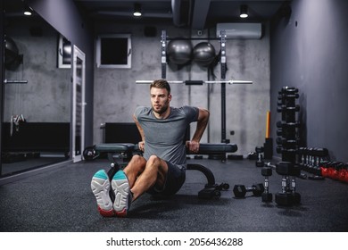 A male athlete does triceps push-ups on a sports bench workout in a modern gym. The concept of fitness training, sports, pumping arm muscles, press ups