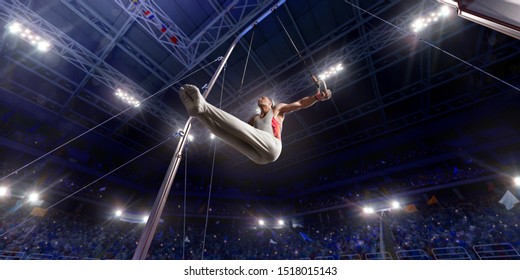 Male athlete doing a complicated exciting trick on gymnastics rings in a professional gym. Man perform stunt in bright sports clothes - Powered by Shutterstock