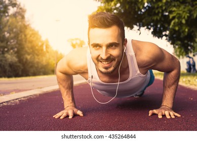 Male athlete exercising pushups outside at sunset. Fit, fitness, exercise and healthy lifestyle concept.