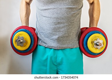 
Male Athlete Holding Up Heavy Dumbbells In Two Hands. Home Workouts During The Coronavirus Pandemic: A Healthy Lifestyle Concept