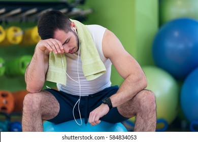 Male Athlete Kneeling Down By Dumbbells Toweling Sweat Of His Brow.