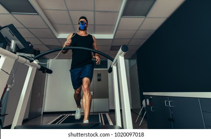 Male Athlete With Mask Running On Treadmill To Analyze His Fitness Performance. Runner Testing His Performance In Sports Science Lab.