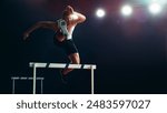 Male Athlete in Mid-air, Leaping Over Hurdle Under Bright Stadium Lights. Agility, Strength, and Determination in High-energy Track and Field Championship Event.