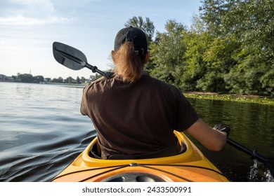 Male athlete paddling kayak on bright sunny day skillfully navigating tranquil lake. Man combines nature walk with water sports - Powered by Shutterstock