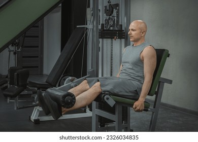 Male athlete performs leg extension on the simulator in the gym - Powered by Shutterstock