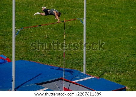male athlete pole vault on background of green field