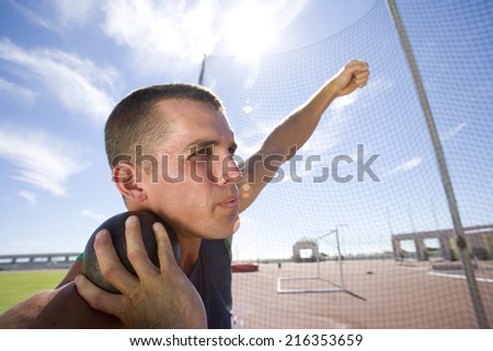 Male athlete preparing to throw shot put ball, low angle view (lens flare)