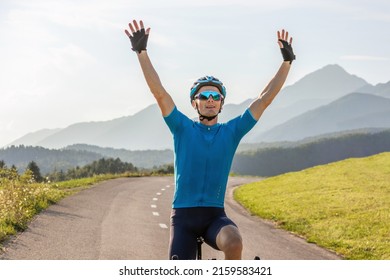 Male athlete professional racing cyclist riding a bike with arms raised above the head, in a victory pose - Powered by Shutterstock