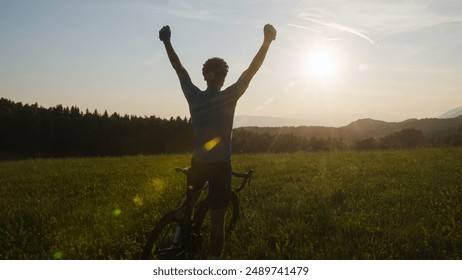 Male athlete professional racing cyclist riding a bike with arms raised above the head, in a victory pose - Powered by Shutterstock