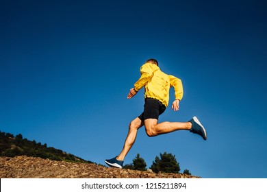 Male Athlete Runner In Yellow Jacket Run Uphill