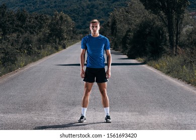 Male Athlete Running On An Empty Road In The Woods While Trying To Get To The Red Finish Line.