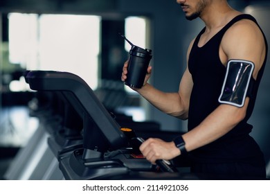 Male Athlete With Sport Shaker And Phone Armband Using Treadmill At Gym, Unrecognizable Sportsman Training On Modern Equipment In Fitness Club, Enjoying Sporty Lifestyle, Cropped Image, Copy Space