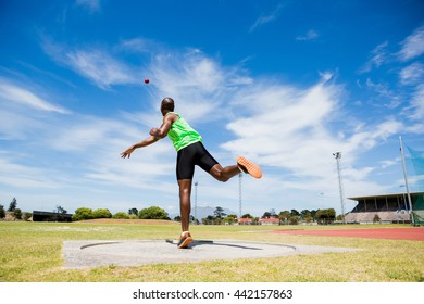 Male athlete throwing shot put ball in stadium - Powered by Shutterstock