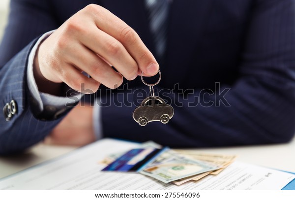 Male auto dealer\
selling car to client. Concept of leasing, investment and sale.\
Shallow depth of field.